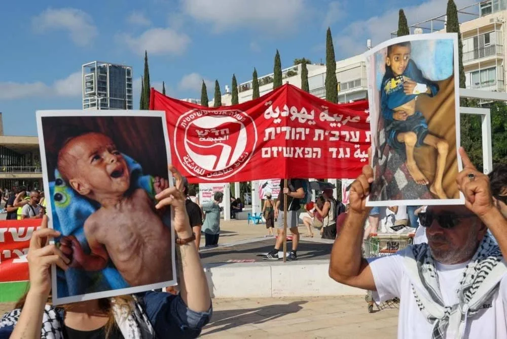 Aktivis membawa foto kanak-kanak Palestin yang mengalami malnutrisi teruk ketika berhimpun di Dataran HaBima di Tel Aviv. Foto AFP