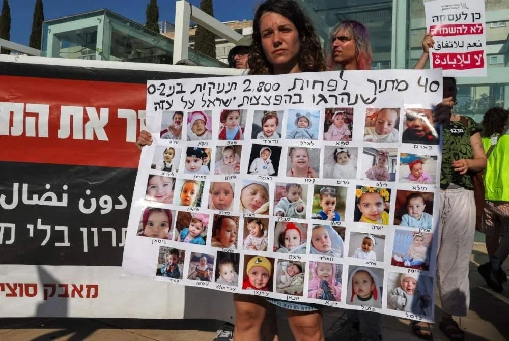 Plakad tertera dalam bahasa Hebrew '40 daripada 2,800 bayi (0-dua tahun) dibunuh dalam kempen pengeboman di Gaza'. Foto AFP