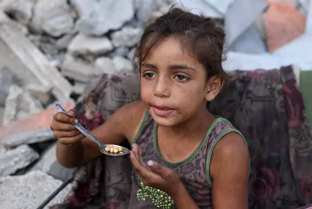 Seorang kanak-kanak perempuan Palestin yang dipindahkan memakan kacang kuda di kejiranan Saftawi, barat Jabalia di utara Semenanjung Gaza, pada 24 Ogos - AFP