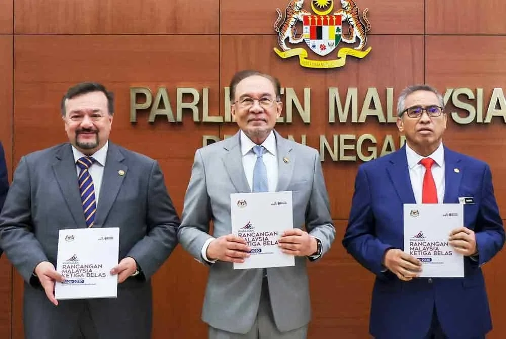 Anwar (tengah) menunjukkan buku RMK13 selepas membentangnya di Dewan Negara pada Isnin. Turut bersama Menteri Kewangan II, Datuk Seri Amir Hamzah Azizan (kiri) dan Ketua Setiausaha Negara, Tan Sri Shamsul Azri Abu Bakar (kanan). Foto Bernama
