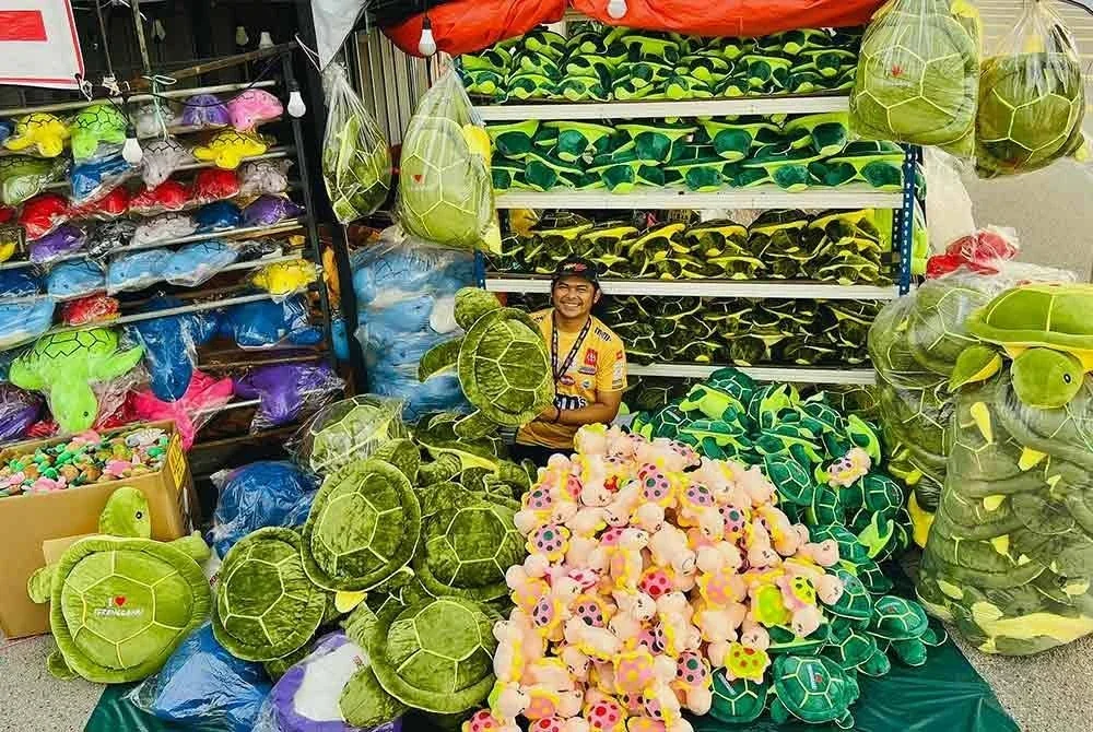 Mohd Azrol atau lebih dikenali sebagai Boss Spark bersama stok patung penyu yang laris dijual.
