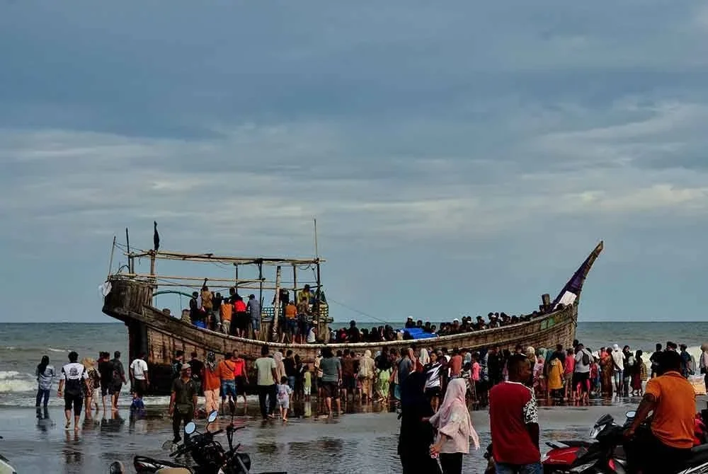 Orang ramai berkumpul mengelilingi sebuah bot yang membawa pelarian Rohingya selepas pihak berkuasa menghalang mereka daripada turun dan mengarahkan supaya terus berada di atas vesel, di Pantai Leuge, Aceh pada 29 Januari 2025.-AFP