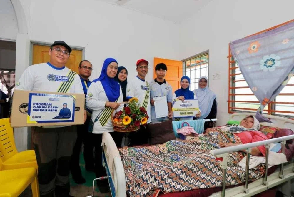 Norliza (dua dari kanan) menyantuni penerima sumbangan dan ibunya semasa Program Ziarah Kasih Simpan SSPN di Taman Gasing, Jejawi, Perlis baru-baru ini.