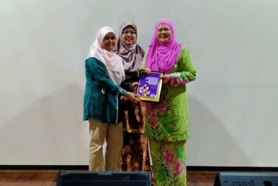 Aziah (kiri) menyerahkan buku hasil Kajian Pengaruh Kepimpinan Ibu Terhadap Motivasi Belajar Anak-anak di Perak: Penghargaan Kendiri Ibu Sebagai Mediator kepada Salbiah selepas membentangkannya di Kompleks Kementerian Dalam Negeri di Ipoh pada Selasa.