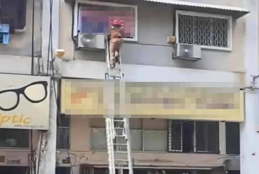 Ahli bomba dari BBP Selayang membantu menurunkan Jalur Gemilang yang dipasang terbalik di sebuah premis di Batu Caves 1, Gombak.