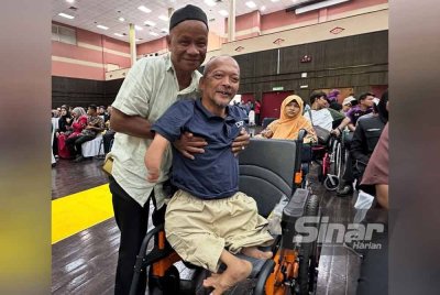 Mahusin didukung Wan Hamdan untuk diletakkan di atas kerusi roda.