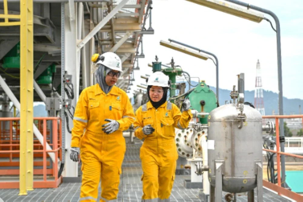 Norhusna (kiri) berbincang mengenai perancangan kerja bersama rakan sekerja di Terminal Gas Terengganu.