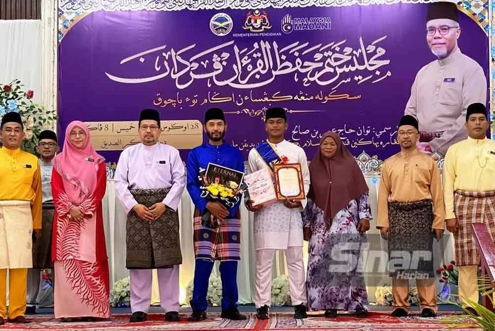 Muhammad Izzuddin (empat dari kanan) berkongsi hari bersejarahnya sebagai hafiz al-Quran bersama ibu bapa, guru-guru dan PIBG pada Majlis Khatam Hafazan Al-Quran Perdana SMK Agama Tok Bachok pada Khamis. Foto: SINAR HARIAN/HAZELEN LIANA KAMARUDIN
