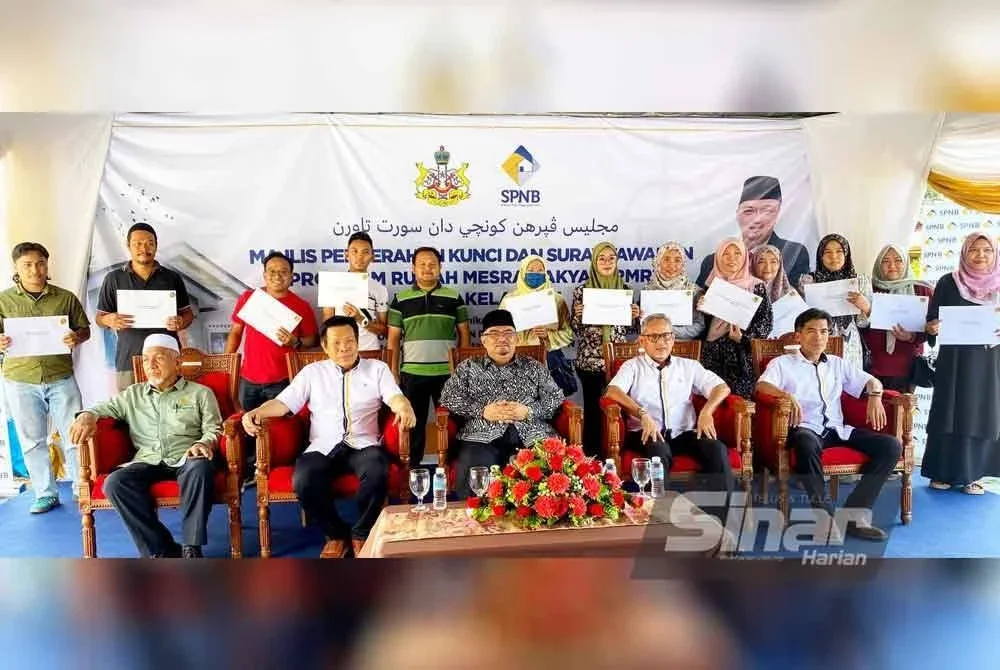 Mohd Azmi (dua dari kiri) bersama Mohamed Fadzli (tiga dari kanan) bersama penerima dan pemohon pada Majlis Penyerahan Kunci dan Surat Tawaran Program Rumah Mesra Rakyat (RMR) di Kampung Banggol Kemian, Paloh Rawa, Machang pada Khamis. Foto Sinar Harian HAZELEN LIANA KAMARUDIN