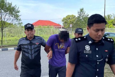 Tertuduh (dua dari kiri) dikawal polis berjalan menuju ke lokap Kompleks Mahkamah Kota Bharu pada Khamis.
