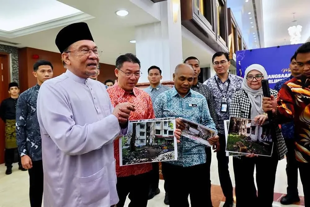 Perdana Menteri Datuk Seri Anwar Ibrahim menunjukkan gambar bangunan rumah yang daif termasuk dalam pelan Malaysia Pembaharuan Semula Bandar (PSB) selepas sesi soal jawab pada Mesyuarat Kedua Penggal Keempat Parlimen ke-15 Persidangan Dewan Rakyat di Bangunan Parlimen pada Khamis. Foto Bernama