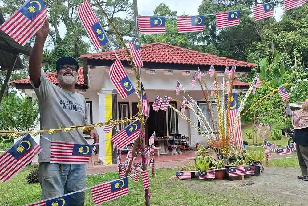 Razali dan Zaliha menghiasi halaman rumah mereka dengan Jalur Gemilang.