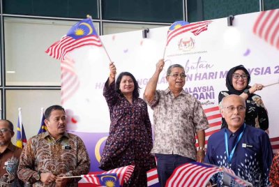 Aaaron mengibarkan Jalur Gemilang ketika Majlis Pelancaran Bulan Kebangsaan Kementerian Perpaduan Negara di Putrajaya baru-baru ini.