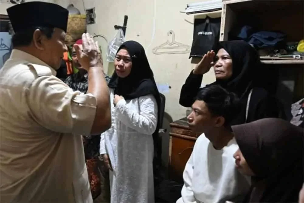 Prabowo (kiri) memberi tabik hormat kepada ibu mangsa ketika kunjungannya pada malam Jumaat. Foto Agensi