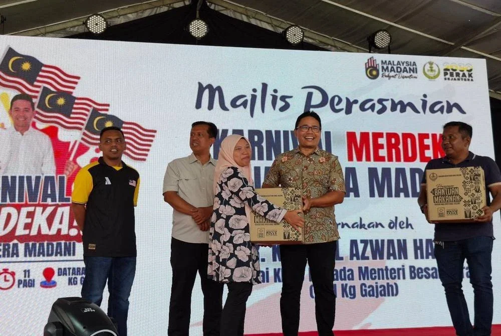 Khairul Azwan menyampaikan kotak program bantuan makanan kepada peserta terpilih sempena Karnival Merdeka Sejahtera Madani di Dataran UMNO Kampung Gajah pada Sabtu.