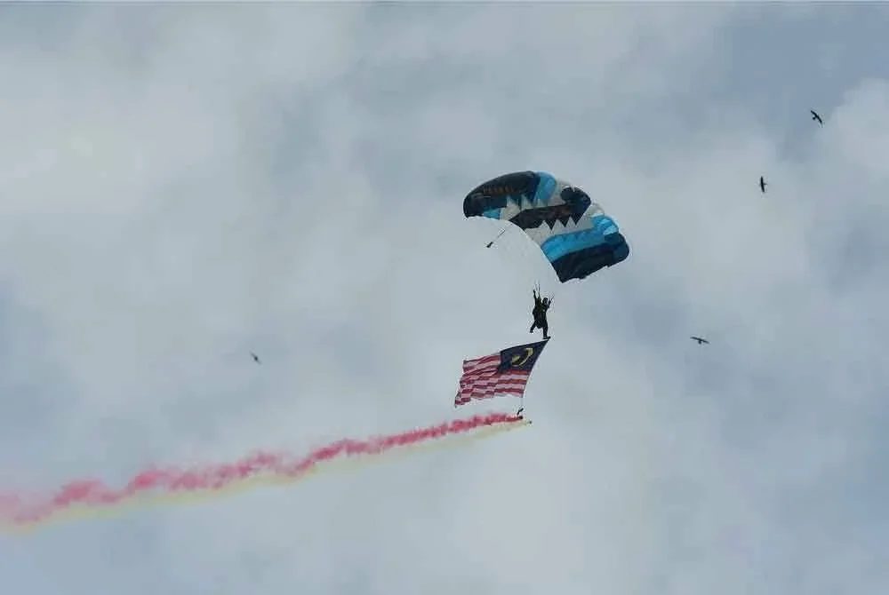 Penerjunan dimulakan Pegawai Waran 1 PASKAL, Mohd Kamil Mustafa membawa Jalur Gemilang dan mendarat di hadapan pentas utama Dataran Medan Bandar.
