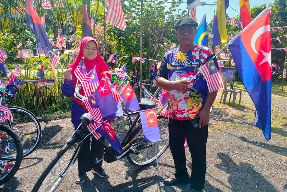 Shamsi dan Tujimah menunjukkan Jalur Gemilang dan bendera Johor yang menghiasi kediaman mereka.