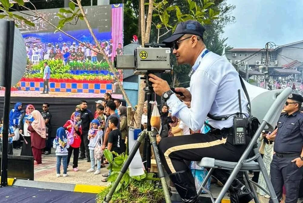 Aksi Koperal Nik Fadhlur Rahman ketika merakam aksi pengguna jalan raya bersama teh ais ikat tepi. Foto ihsan PDRM