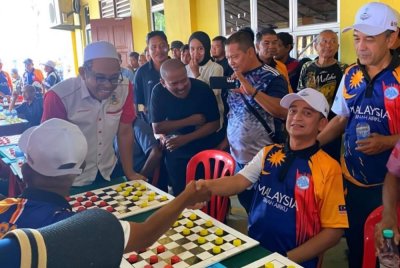 Muhammad Faiz (kanan) turut sama mengikuti permainan dam aji bersama nelayan pada program Gelombang Samudera Madani Kelantan Sempena Hari Kebangsaan 2025 di Pantai Sri Tujoh, Tumpat pada Ahad.