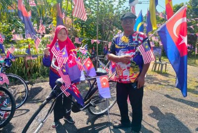 Shamsi dan Tujimah menunjukkan Jalur Gemilang dan bendera Johor yang menghiasi kediaman mereka.