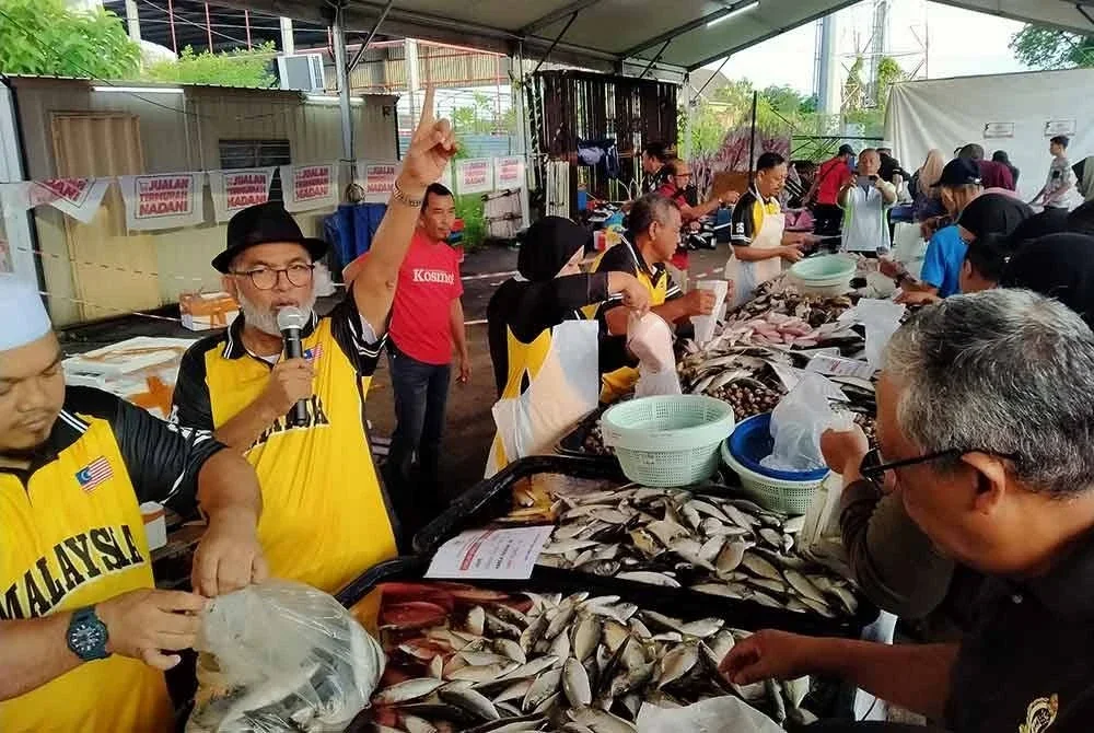 Syed Abu Hussin (dua dari kanan) membuat jualan ikan sempena Jualan Termurah Madani di Pusat Khidmat Parlimen Bukit Gantang pada Isnin.