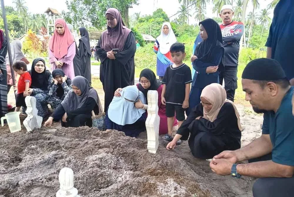 Anak-anak Allahyarham Abdul Rahim dan Allahyarhamah Norhasriah tidak dapat menahan sebak ketika pengebumian kedua ibu bapa mereka di Tanah Perkuburan Kampung Serating, Marang pada Isnin.