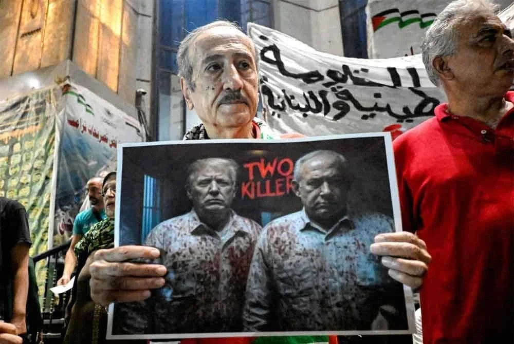 Penunjuk perasaan di Kaherah memegang plakad mengkritik Donald Trump dan Benjamin Netanyahu ketika bantahan solidariti bersama wartawan Gaza. - AFP