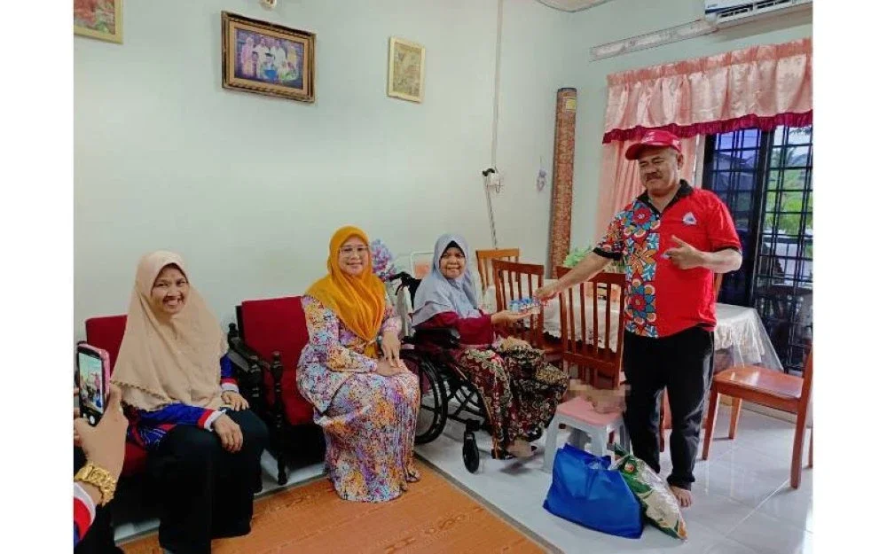Hamzah (kanan) menyampaikan sumbangan kepada warga emas, Ramlah Ab Manaf sambil disaksikan Norasnira (dua dari kiri).