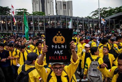 Seorang mahasiswa memegang poster mengecam polis susulan kematian pemandu penghantar selepas dilanggar kenderaan taktikal di Jakarta. - Foto: AFP