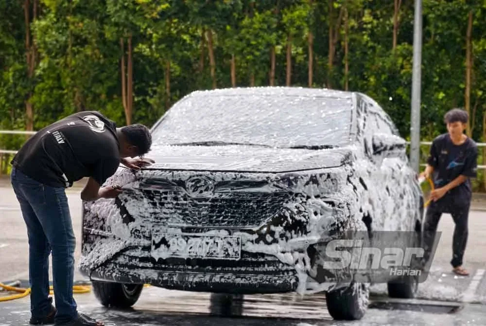 Dua pekerja Dad Carwash sedang mencuci kereta pelanggan.