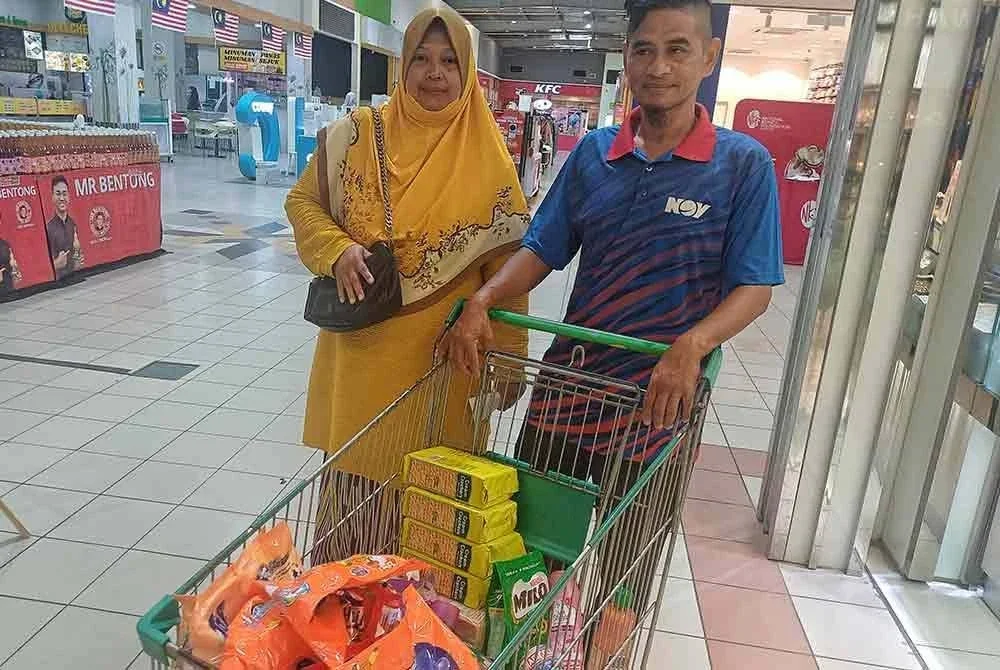 Mak Lini dan Safari menunjukkan barangan keperluan yang dibeli. Foto Sinar Harian.