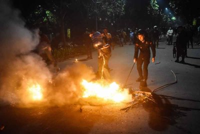 Seorang pegawai polis memadamkan kebakaran yang dibuat oleh penunjuk perasaan di hadapan ibu pejabat Polis Metro Bekasi di Bekasi, Jawa Barat, di tengah-tengah pertempuran yang dikaitkan dengan gelombang protes yang telah merebak di seluruh bandar utama. Foto AFP