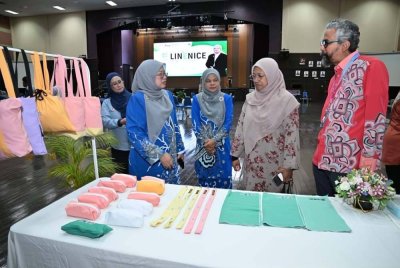 Aziah (dua dari kanan) melihat beg, bekas pensel dan pelbagai kraftangan lain yang dihasilkan daripada kain linen terpakai.