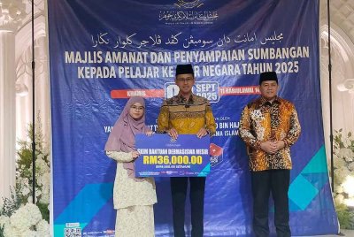 Mohd Fared (tengah) menyampaikan sumbangan kepada pelajar yang akan menyambung pengajian ke luar negara.