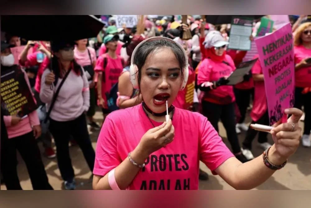 Aksi salah seorang penunjuk perasaan yang sempat menyapu semula gincu ketika sedang berhimpun. Foto Agensi 