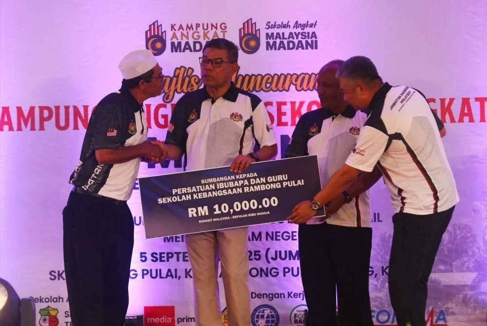 Saifuddin menyerahkan sumbangan kepada penerima dalam Majlis Peluncuran Kampung Angkat dan Sekolah Angkat Madani.