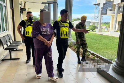 Suspek (dua dari kiri) dikawal ketat polis berjalan menuju ke bilik mahkamah.