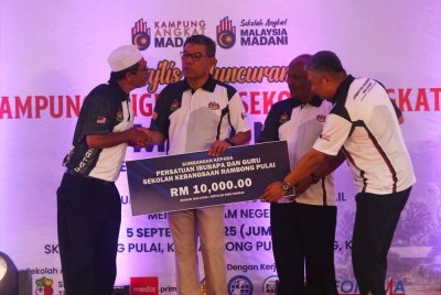 Saifuddin menyerahkan sumbangan kepada penerima dalam Majlis Peluncuran Kampung Angkat dan Sekolah Angkat Madani.