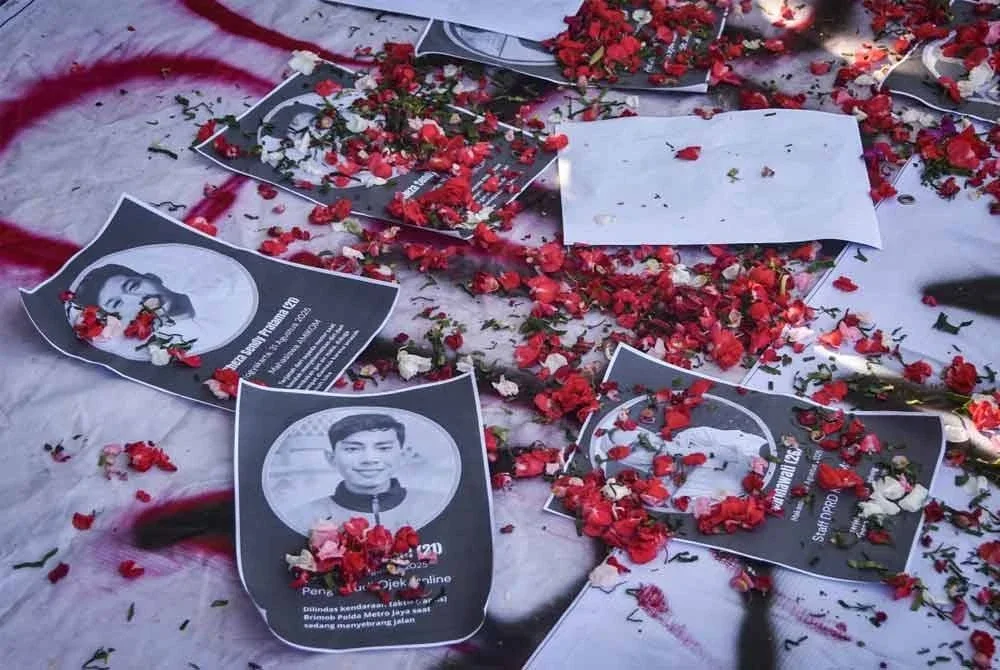 Kelopak bunga ditabur pada potret mangsa rusuhan semasa majlis memperingati di Bekasi, Jawa Barat. - AFP