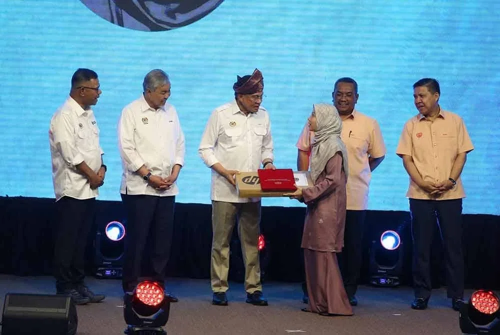 Muhammad Sanusi (dua dari kanan) menyaksikan Anwar menyampaikan peranti Madani kepada pelajar sempena Program Madani Rakyat di Majlis Daerah Baling pada Sabtu.