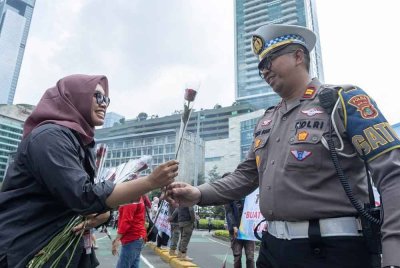 Seorang wanita menyerahkan bunga mawar kepada anggota polis semasa demonstrasi aman di Tanah Abang, Jakarta. - AFP