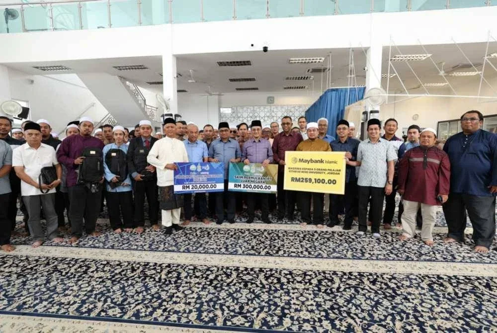 Mohamad (tengah) menyerahkan replika cek biasiswa dan Skim Permulaan IPT Luar Negara kepada pelajar yang bakal melanjutkan pengajian ke Timur Tengah.