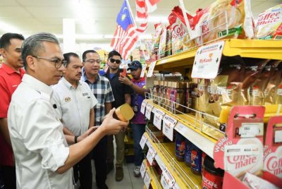 Fahmi melihat harga barangan yang dijual pada harga Rahmah ketika meninjau penggunaan Sumbangan Asas Rahmah (SARA) di sebuah pasaraya di Merotai pada Ahad. Turut hadir, Ketua Setiausaha Kementerian Komunikasi, Datuk Seri Mohamad Fauzi Md Isa (dua dari kiri). Foto Bernama