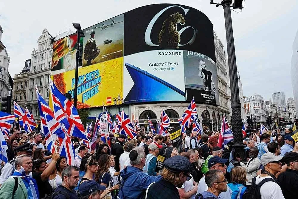 Penunjuk perasaan memegang sepanduk dan mengibarkan bendera semasa demonstrasi 'perarakan menentang antisemitisme' di tengah London pada 7 September 2025 - Foto: AFP