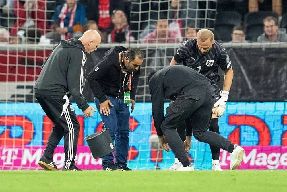 Petugas padang menampal lubang yang muncul ketika aksi kelayakan Piala Dunia 2026 zon Eropah Kumpulan H antara Austria dan Cyprus. - Foto: AFP