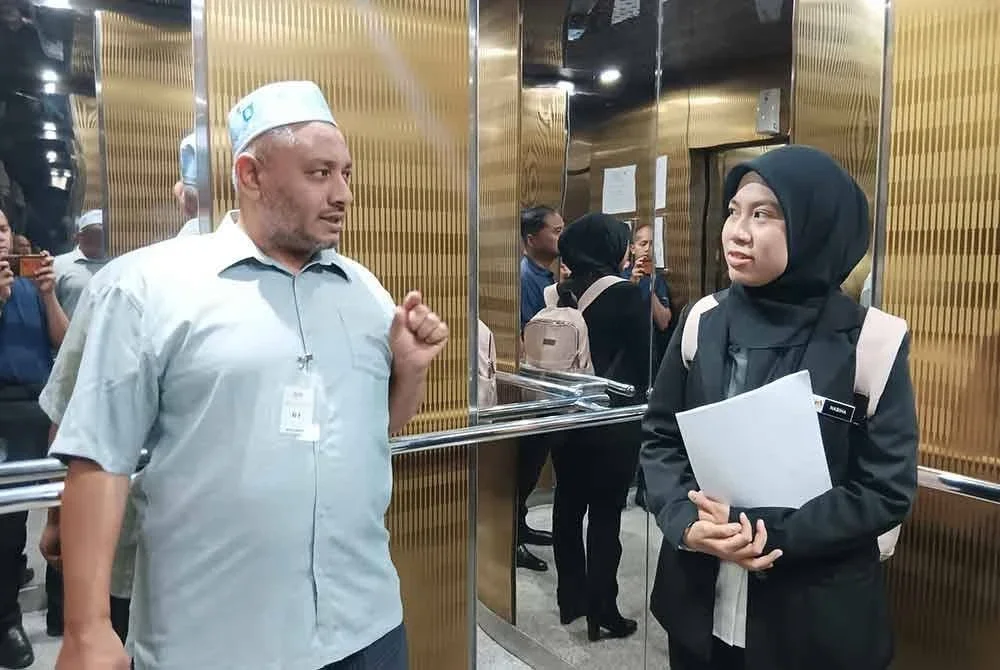 Tertuduh (kiri) ketika tiba di Mahkamah Majistret di Kuala Terengganu.