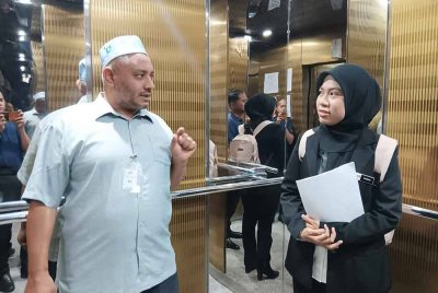 Tertuduh (kiri) ketika tiba di Mahkamah Majistret di Kuala Terengganu.