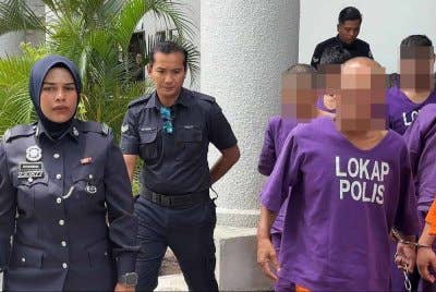 Suspek (depan, kanan) diiringi anggota polis ketika dibawa ke Mahkamah Butterworth pada Isnin.