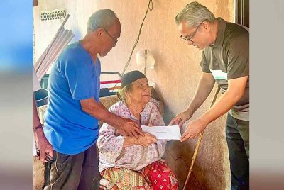 Azran Fitri (kanan) menyampaikan sumbangan zakat kepada Zainab Mat Didah, 78, yang menderita akibat serangan angin ahmar di Kampung Banggol, Sik, Sabtu lalu.