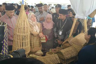 Tunku Azizah Aminah Maimunah diiringi Ahmad Zahid meninjau pelbagai produk kraf tangan Orang Asli yang dipamerkan sempena majlis perasmian PLPB pada Selasa.
